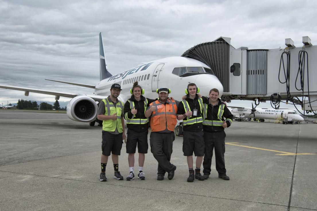 Baggage handlers in front of airplane.