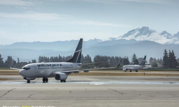 Airplane on runway with mountain in background.